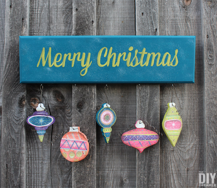 Hand painted Merry Christmas Sign with Hanging Ornaments. This entire project was hand painted! A beautiful DIY Christmas sign using fun colors! Click through for the tutorial: thediydreamer.com