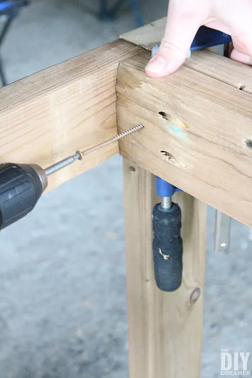 Add decking screws to attach the legs to the table frame.