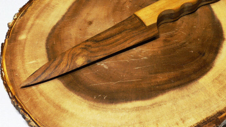 Wooden cake knife on a wood cutting board.